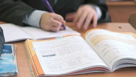 Boy sitting at the desk making home task at school Stock Footage 69836310
