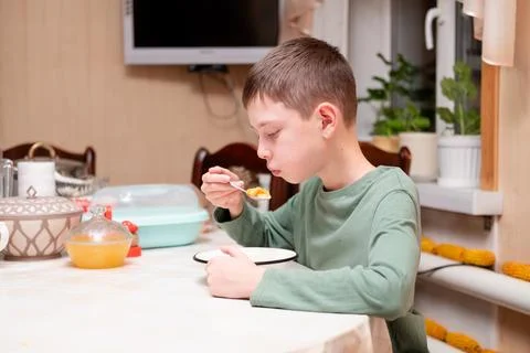 Boy sitting at the dining table and eating breakfast cereal Stock Photos