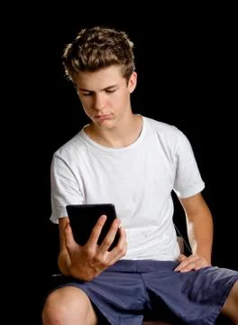 Boy sitting with ebook reader or tablet in his hand Stock Photos