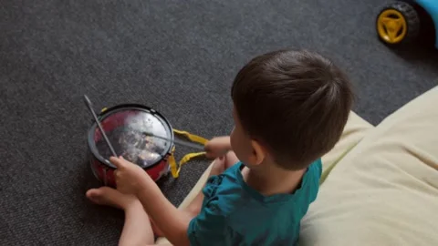 Boy sitting on floor and playing with plastic toy drum. Top view. Stock Footage 168387121