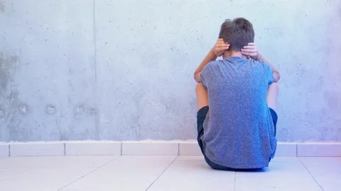 Boy sitting on the floor closing his ears with hands. Autism awareness concept Stock Footage 134468485