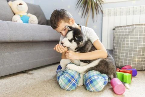 A boy sitting on the floor with his husky puppy Stock Photos