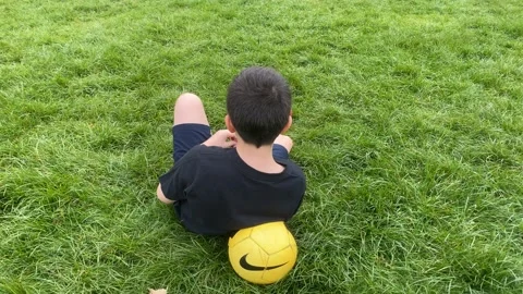 Boy sitting on the floor int he park Stock Footage 183826371