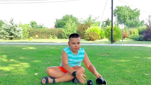 Boy Sitting on Grass in Lotus Pose Meditating with Headphones Nearby Video stock 342589360