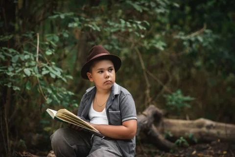 Boy sitting on the ground holding an open book Foto stock
