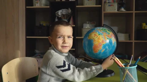Boy sitting at his desk with a globe Video stock 103470068