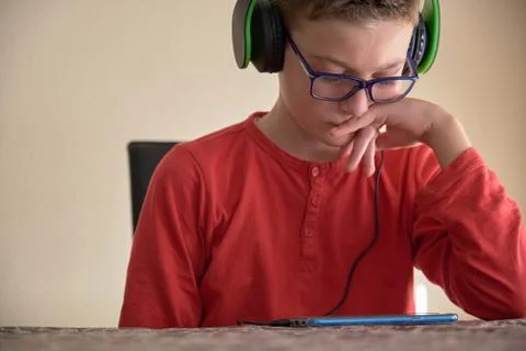 Boy sitting at home using his mobile phone with headphones Stock Photos
