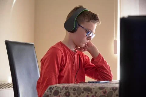 Boy sitting at home using his mobile phone with headphones Stock Photos
