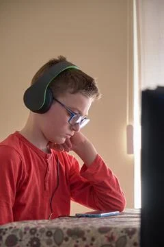 Boy sitting at home using his mobile phone with headphones Stock Photos