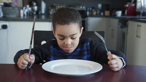 Boy sitting at the kitchen table with empty plate Stock Footage 143046537