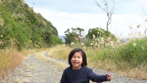 A Boy Sitting on a Mountain Path in Nature, Chatting with a Smile Stock Footage 333186155