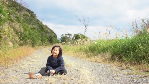 A Boy Sitting on a Mountain Path in Nature, Chatting with a Smile Stock Footage 333186162