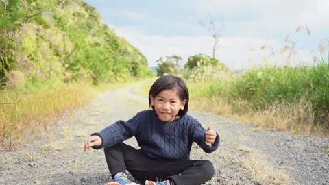 A Boy Sitting on a Mountain Path in Nature, Sneezing and Chatting with a Smile Stock Footage 333186173