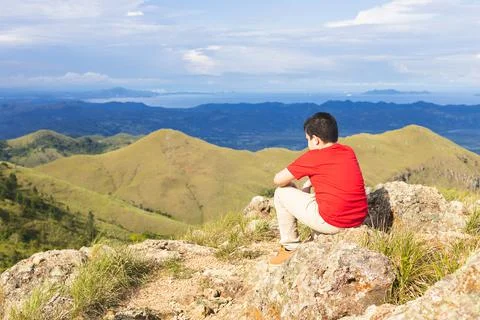 Boy sitting on the mountain thinking Stock Photos
