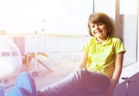 Boy sitting next to window and looking at airplane Stock Photos