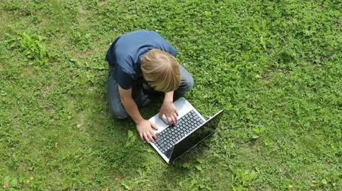 Boy sitting outdoors at laptop Stock Footage 12185408