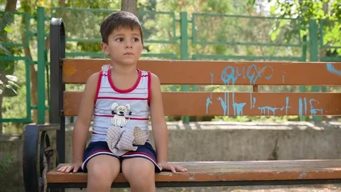 Boy sitting on a park bench Stock Footage 75811317