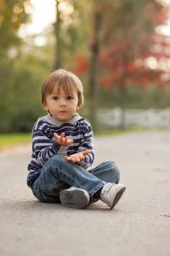 Boy, sitting on a path in a park Stock Photos