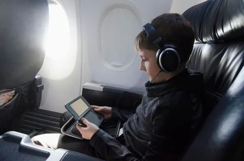 Boy sitting in plane and playing video game Foto stock