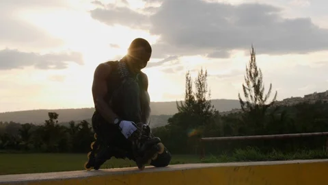 Boy sitting on the ramp and putting on rollerblades. Vídeo Stock 110865341