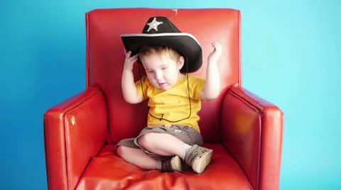 Boy sitting in red chair Stock Footage 20634690