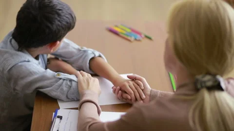 Boy sitting in silence during session with young psychologist. holding the hand Stock Footage 69001330