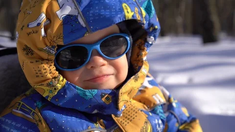 Boy sitting on a sled in winter overalls Stock Footage 104028465