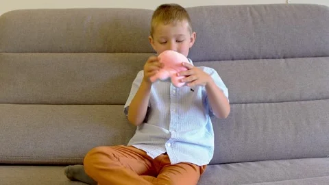 The boy is sitting on the sofa and playing with a toy octopus Video stock 168074439