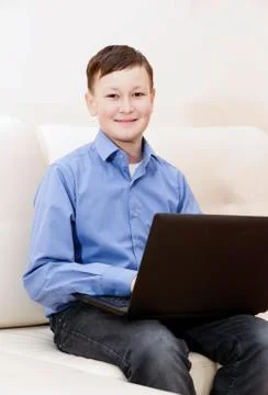 Boy sitting on sofa with laptop Stock Photos