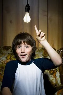 Boy sitting on sofa with light bulb idea Stock Photos