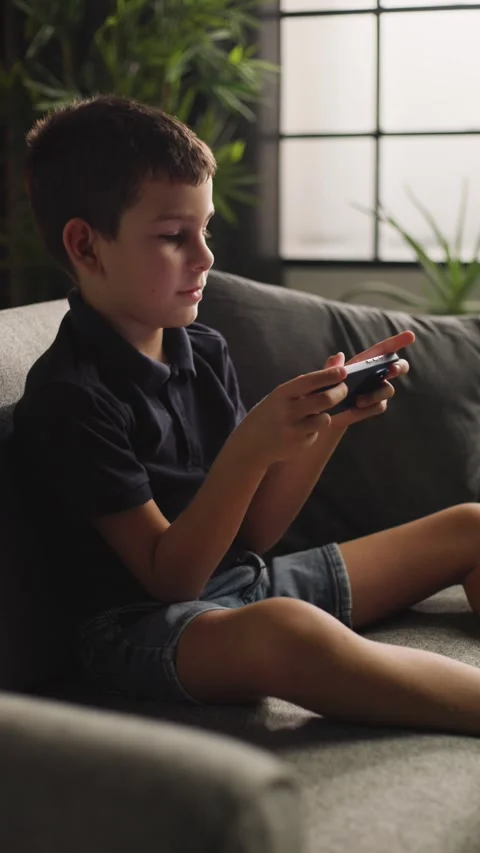 Boy Sitting on Sofa Playing Mobile Game on Phone Video stock 344146118
