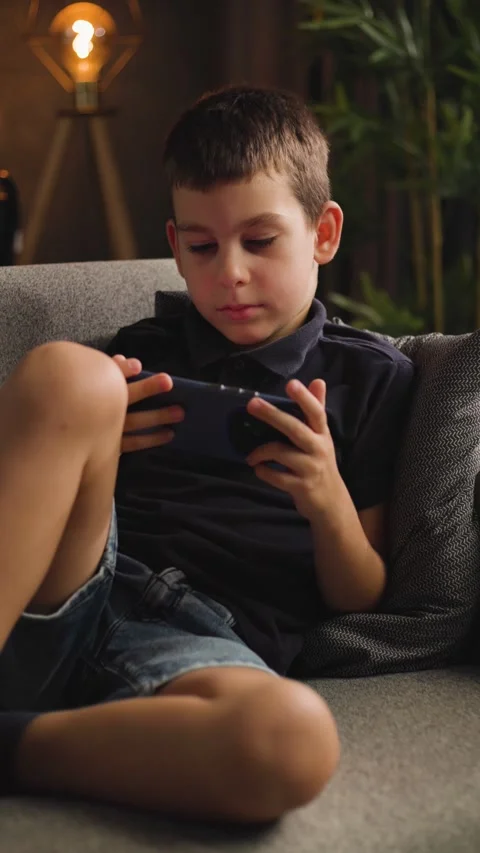 Boy Sitting on Sofa Playing Mobile Game on Phone Video stock 344146235