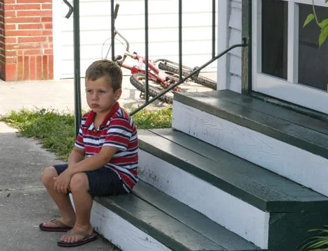 Boy sitting at the steps of the house 库存照片