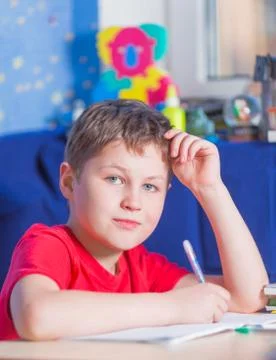 Boy sitting at the table and doing his homework Stock Photos