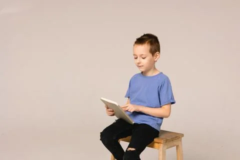 The boy is sitting at the table and is undergoing online trening. Foto stock