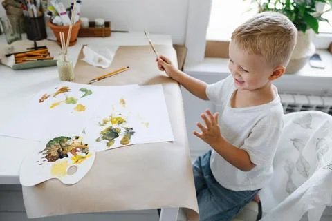 Boy sitting at the table drawing with paints Stock Photos