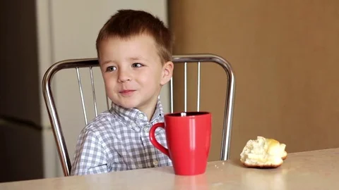 A boy sitting at the table drinkink tea Stock Footage 74053666