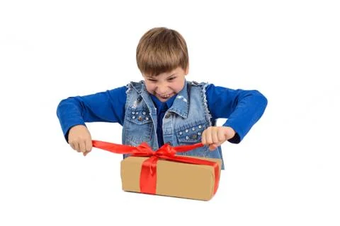 The boy is sitting at the table, in front of him is a gift in paper packaging Stock Photos