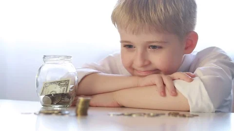  boy sitting at a table with money Stock Footage 70136456