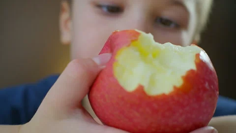 A boy sitting at a table savoring an apple. close-up Stock Footage 295003571