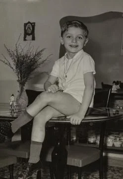 Boy sitting on table wearing undershirt, socks and shoes in domestic settin.. Stock Photos