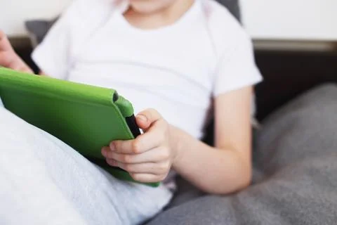 Boy sitting with a tablet on bed.Distance learning online education. Child wi 写真素材