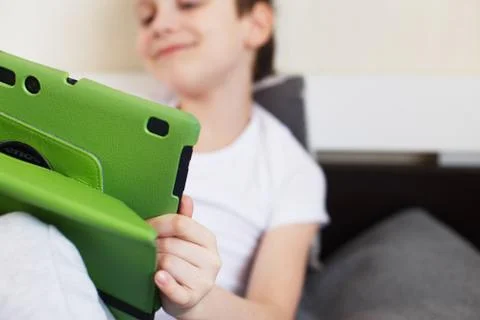 Boy sitting with a tablet on bed.Distance learning online education. Child wi 스톡 사진