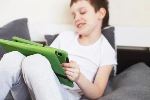 Boy sitting with a tablet on bed.Distance learning online education. Child wi Foto stock