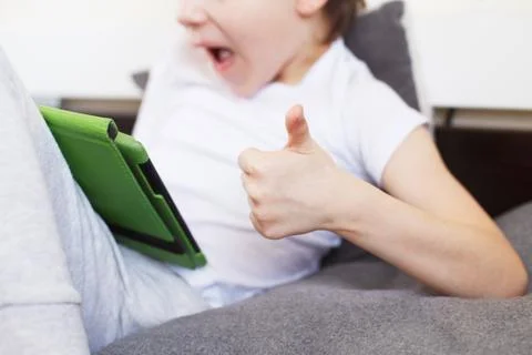 Boy sitting with a tablet on bed.Distance learning online education. Child wi Stock Photos