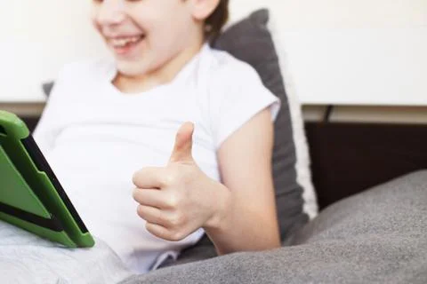Boy sitting with a tablet on bed.Distance learning online education. Child wi Foto stock