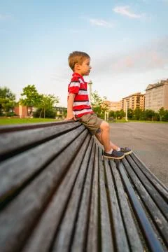 Boy sitting on the top of bench park relaxing Foto stock