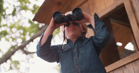 Boy sitting in a treehouse looking through binoculars Stock Footage 61296024