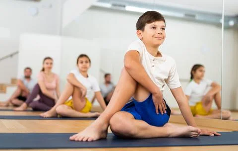 Boy sitting in twisting asana Matsyendrasana during family yoga class Stock Photos