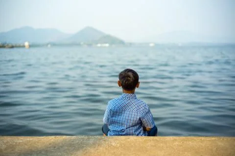 The boy sitting on the waterside  overlooking view at Bang Phra reservoir cho Stock Photos